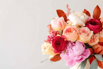 A beautiful bouquet of peonies and roses in shades of pink, red and cream, with leaves hanging down on a light background. Delicate floral greeting card