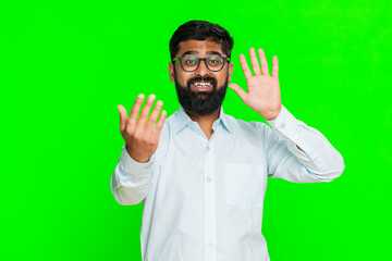 Indian man waves hand quickly with cheerful expression, inviting someone to come closer or enter...