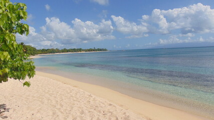 La plage de sable blanc et la mer turquoise sous le ciel bleu