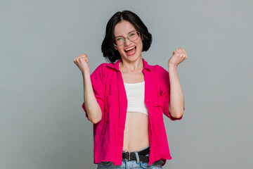 Young woman smiles brightly celebrating a major win, showing happiness from success or personal...