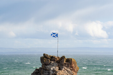 The Scottish flag flying in the wind next to the sea