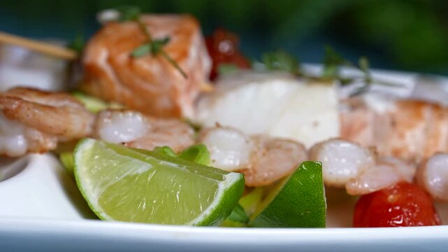 Seafood skewers with shrimp, salmon, and cod, garnished with fresh lime slices and green herbs.