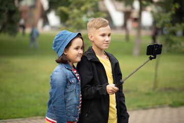 Girl and boy teenagers bloggers influencer records videos from the blog on a smartphone outdoor....