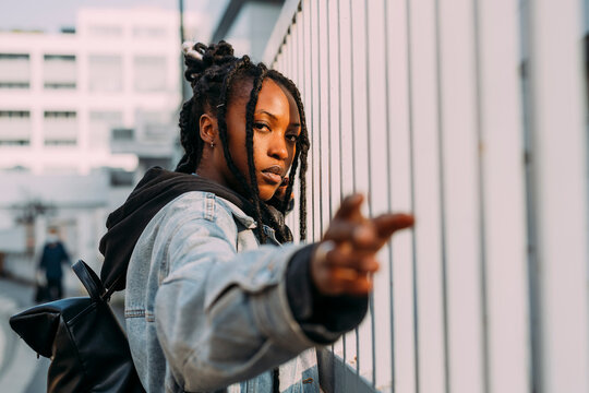 Woman with backpack gesturing at fence