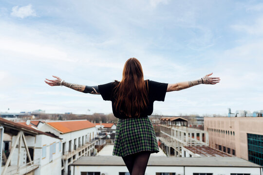 Woman with arms outstretched standing on building terrace