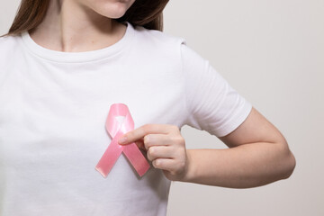 Woman wearing pink ribbon symbol of fight against breast cancer. Concept of breast cancer campaign and support movement.