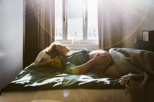 Pregnant woman lying on bed at home