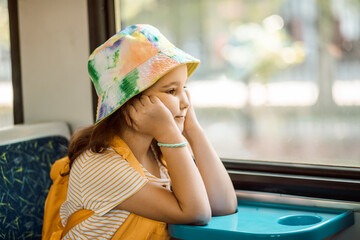 Little cute girl looking out train window outside while it moving. Travel, tourism, vacation and family concept.