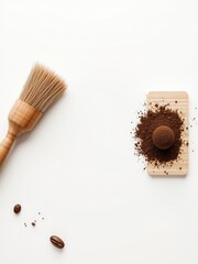 A rustic wooden brush and fresh roasted coffee beans arranged with ground powder on a simple light board, perfect for morning rituals.