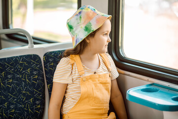 Little cute girl looking out train window outside while it moving. Travel, tourism, vacation and family concept.