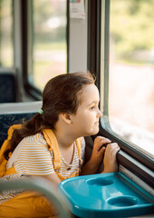 Little cute girl looking out train window outside while it moving. Travel, tourism, vacation and family concept.
