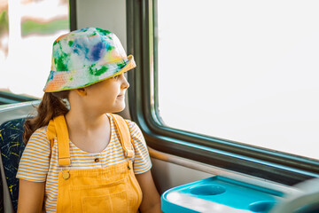 Little cute girl looking out train window outside while it moving. Travel, tourism, vacation and family concept.