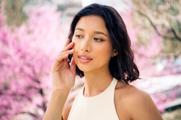 Beautiful young woman in a blooming garden enjoying a sunny spring day outdoors