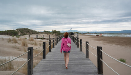 Tourist walking on wooden footbridge to the beach on cloudy day