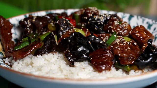 Rich stir-fry with beef slices, glossy mushrooms, green beans, red peppers, and sticky white rice.