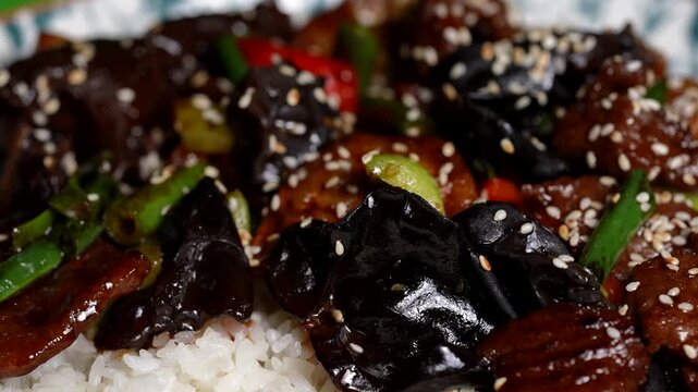 Steamed rice topped with stir-fried black fungus, green beans, bell peppers, beef, and sesame seeds.