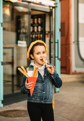 Cute little girl eating traditional Spanish treat street fast food churros. Food delivery or take away food concept.