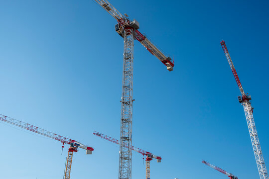 Multiple construction cranes against blue sky in real estate zone, illustrating the intensity of urban development and high demand for modern residential infrastructure.