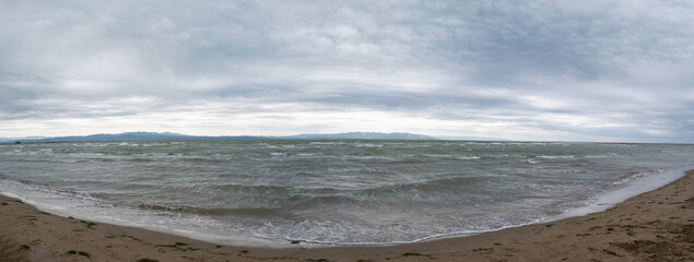 Wide shot of stormy sea waves hitting the shore on a cloudy day