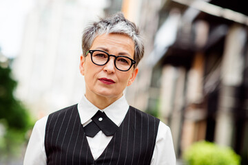 Confident professional businesswoman with short hair wearing stylish formal attire standing in an...