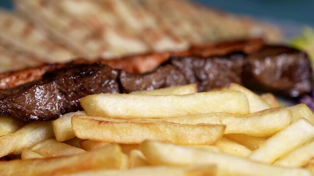 Beef and chicken skewers with crispy fries and fresh purple onions, served on a plate.
