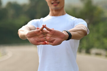 Close up with a Fit male athlete doing hand stretches and warming up in a natural outdoor setting...