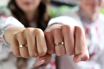 The hands of the newlyweds with wedding rings are clenched into fists.