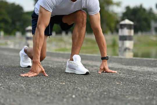 Close-up of a male athlete in starting position for a sprint, hands on the ground, ready to run on an outdoor track