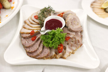 A plate with sliced meat and sauce on a festive table.