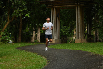 Active man running in sportswear through a lush green park, representing health, fitness, and outdoor activity