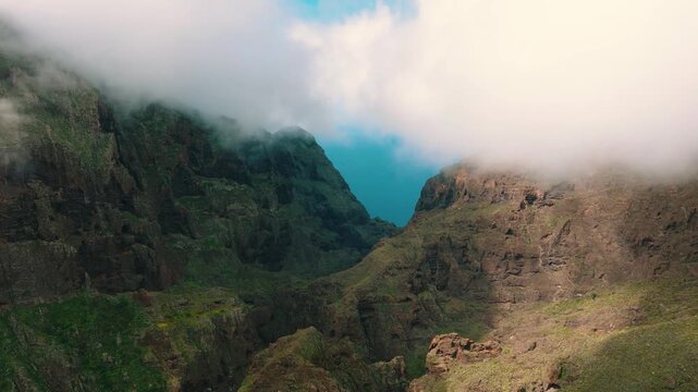 Aerial view of Masca village gorge opening to the turquoise ocean through dramatic cliffs and clouds, Tenerife, Canary Islands
