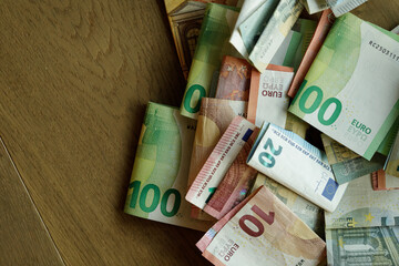 High-angle close-up of various euro banknotes on a wooden surface. Ideal for finance, economy, and...