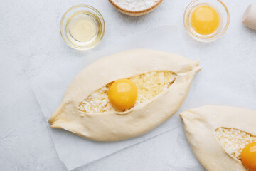 Closeup of khachapuri with egg yolk and flour on white table