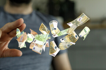 Image of a man's hand reaching for floating euro banknotes.  Perfect for finance, wealth, or...