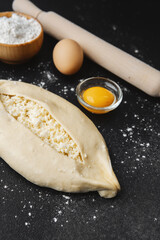 Floured surface with raw khachapuri, eggs and rolling pin for baking