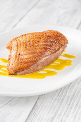 Whole Crispy Duck Breast on Mustard Lemon Honey Sauce in White Plate