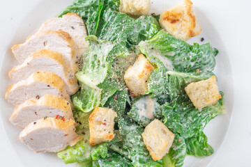 Classic Caesar salad topped with chicken breast served on clean white plate