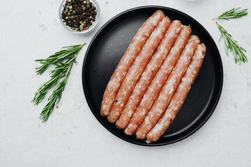 Fresh pork sausages on black plate with rosemary and salt