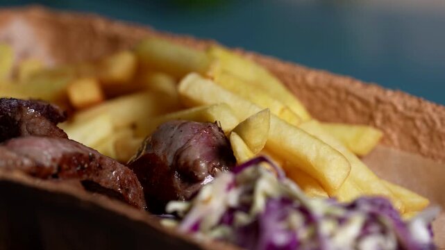 Golden French fries and juicy steak pieces with creamy cabbage slaw, ready to serve in a tray.