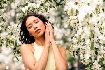Lovely woman enjoying a sunny spring day surrounded by blooming flowers and vibrant greenery in an...