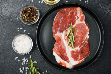 Raw beef steak with herbs and seasonings on black plate