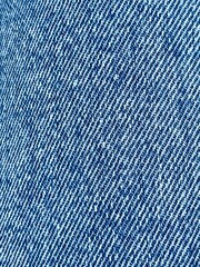 Close-up texture of denim fabric. Classic blue jeans material with diagonal twill weave. Detailed...