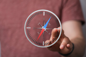 A hand interacts with a digital compass, illustrating navigation, direction, or guidance.