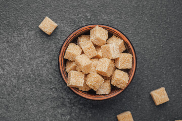 Brown sugar cubes arranged in a rustic bowl on a dark surface