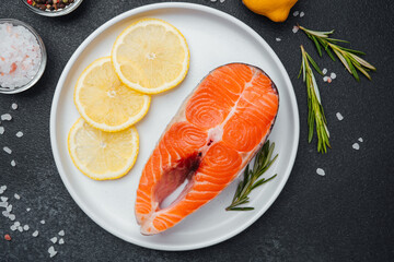 Fresh salmon fillet garnished with lemon slices and herbs on a white plate