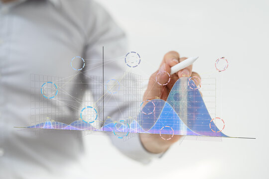 Stock photo of a businessman analyzing data charts and graphs using a stylus on a digital screen.