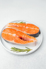 Fresh salmon fillets with rosemary on a white plate ready for cooking