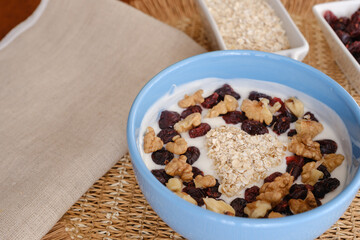 Heart-shaped oat flakes on a bowl of yogurt with walnuts and dried cranberries
