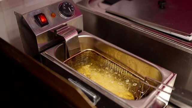 Raw potato fries loaded into fryer basket, ready for deep frying.