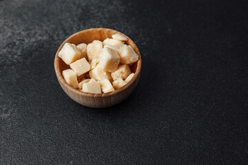 Chopped cheese cubes served in a wooden bowl on a dark surface